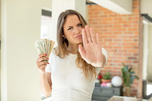 A woman holding banknotes and raising her other hand
